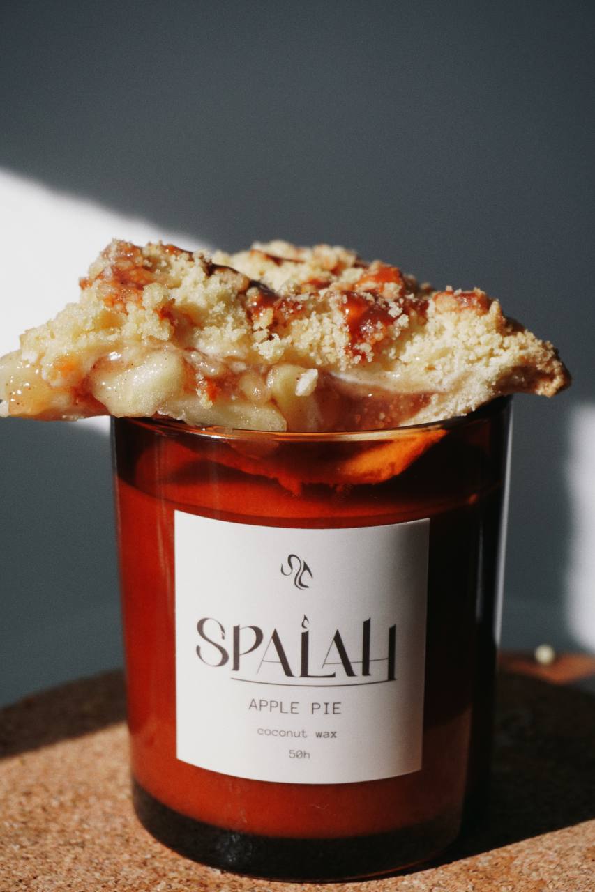 Red candle 'Apple Pie' with a slice of apple pie resting on top of the container